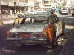 Smashed up taxi at bomb site.