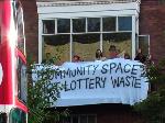 "Community Space or Lottery Waste?" banner on the Social Centre's balcony