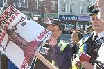 Plucky pensioner's placard prevents police photographer from snapping speakers.