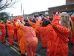 and people in orange jump suits doing the "shackle-shuffle"