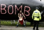 A protester stands in front of an inflatable 'bomb' while being watched