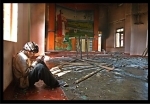 A tribal christian praying in a burnt down church