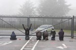 Activists kneel in prayer in front of the gates of Northwood