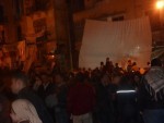 crowd around TV screens to watch news of the revolution