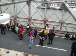 protesters in plastic cuffs awaiting transport off the bridge by bus