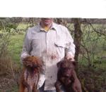 A hunter proudly displays a magled fox and his dog after a dig-out