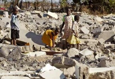 Zimbabwean children scavenge for pieces of wood from the rubble of a destroyed h