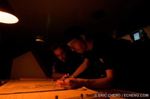 Crew members on the bridge looking over navigation charts